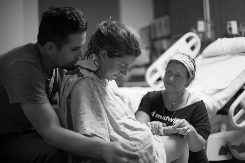 Rita supporting a labouring mother and her partner in a hospital room