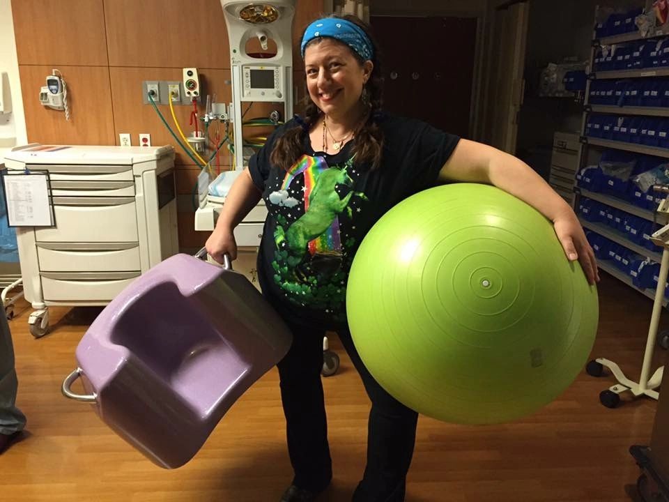 Rita in a hospital room carrying a birth ball and peanut ball