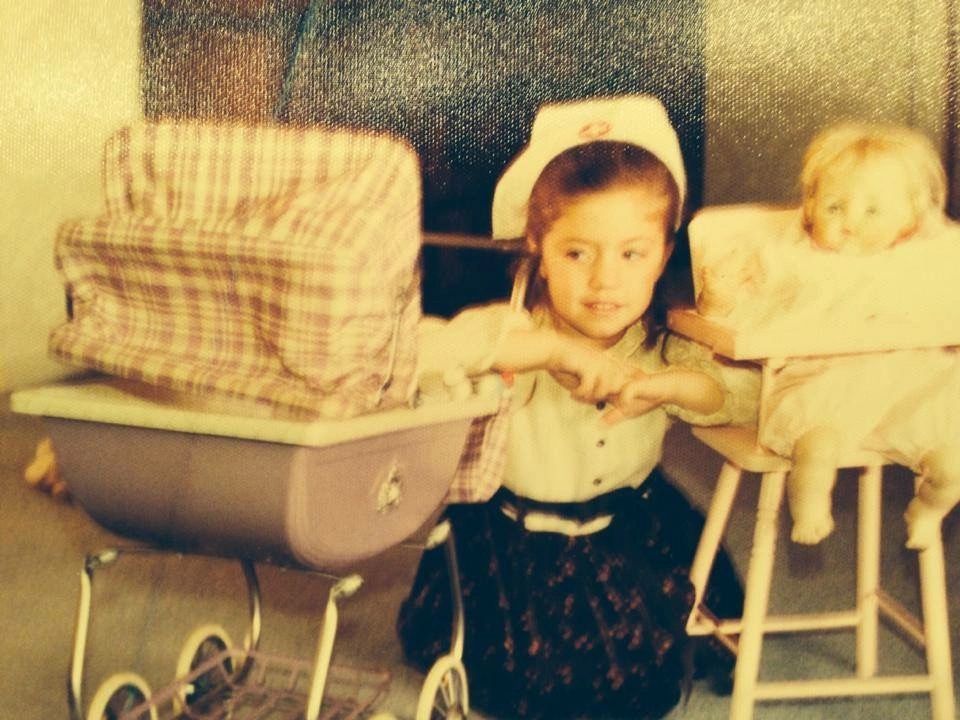 Rita as a small child with a toy pram and nurse cap